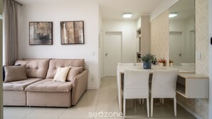 Un saló modern amb un sofà seccional beix, una taula de dinar amb cadires i un mirall gran.