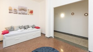 Ein modernes Wohnzimmer mit einem weißen Sofa, einem blauen Teppich und Kunstwerken an der Wand.