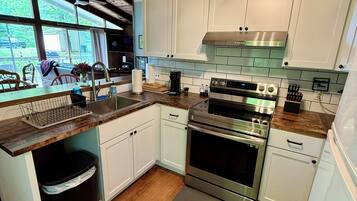 A modern kitchen with white cabinets, stainless steel appliances, and a large window.
