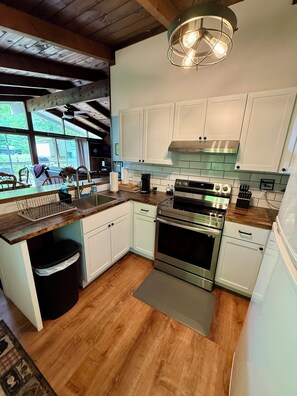 A modern kitchen with white cabinets, stainless steel appliances, and a large window.