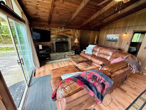 Ein gemütliches Wohnzimmer mit Kamin aus Stein, Ledersofa und Fernseher.