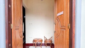 A hallway with two wooden doors, a chandelier, and a small table with chairs.