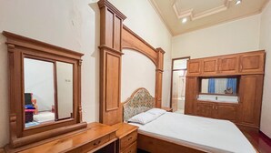 A bedroom with a wooden bed, a wooden desk, and a mirror.