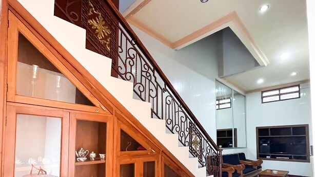 A staircase with ornate railings leading to a living area with a sofa and a television.