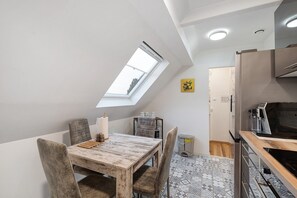 A modern kitchen with a skylight, a dining area with a wooden table, and patterned flooring. - Apartment 'Ortenau' with Wi-Fi (Willstätt)