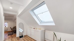 Una habitación moderna con tragaluz, suelo de madera, un armario blanco y una planta en maceta.