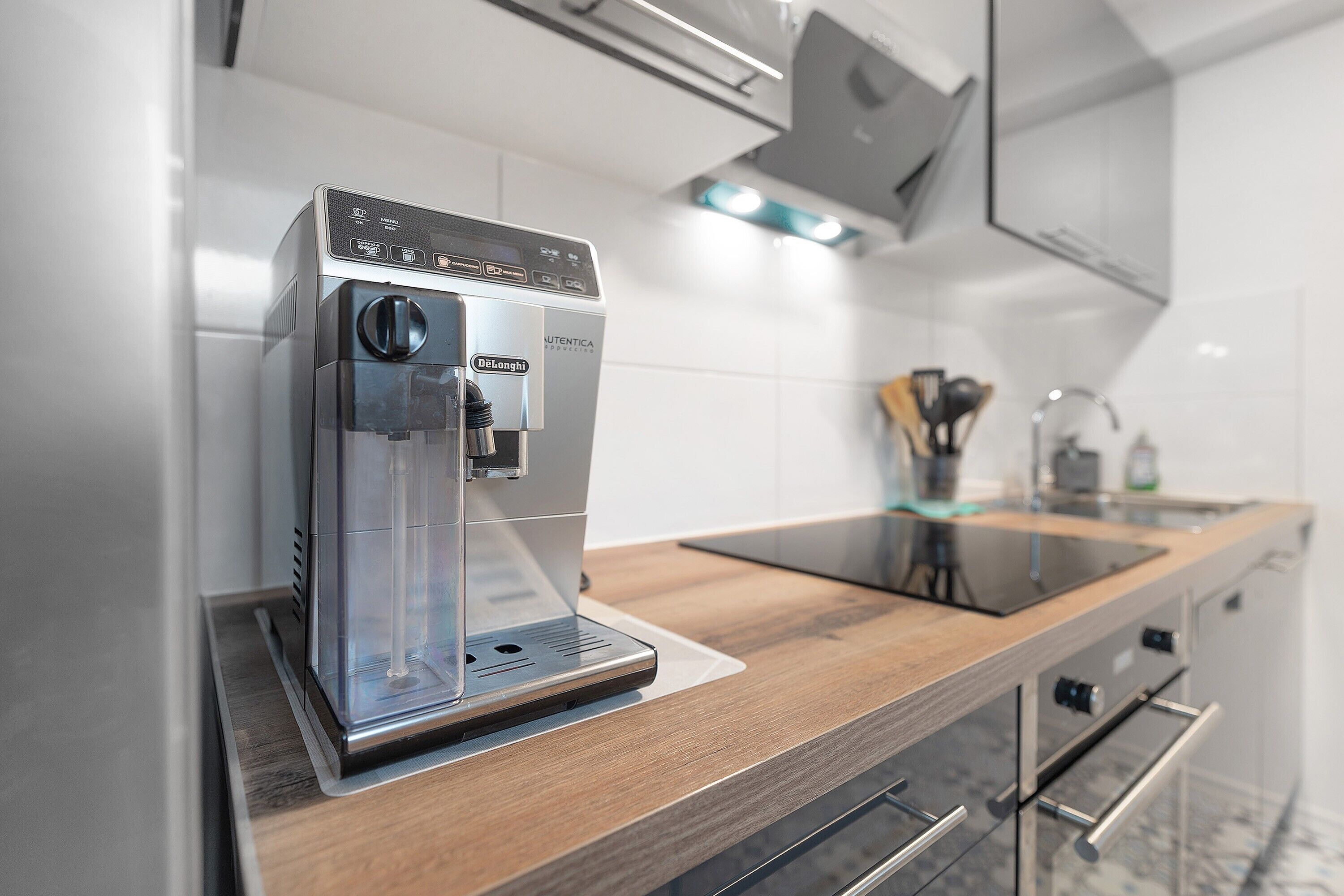 A modern kitchen with a built-in coffee machine, a wooden countertop, and stainless steel appliances.