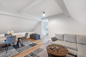 A modern loft with a dining area, sofa, and a small table with a remote control. - Apartment 'Ortenau' with Wi-Fi (Willstätt)