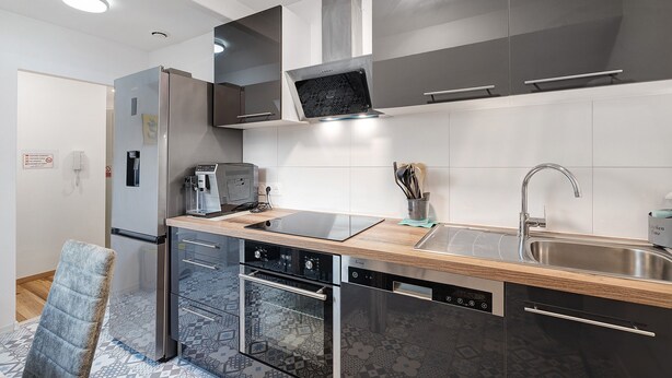 Una cocina moderna con horno integrado, lavavajillas y pileta de acero inoxidable.