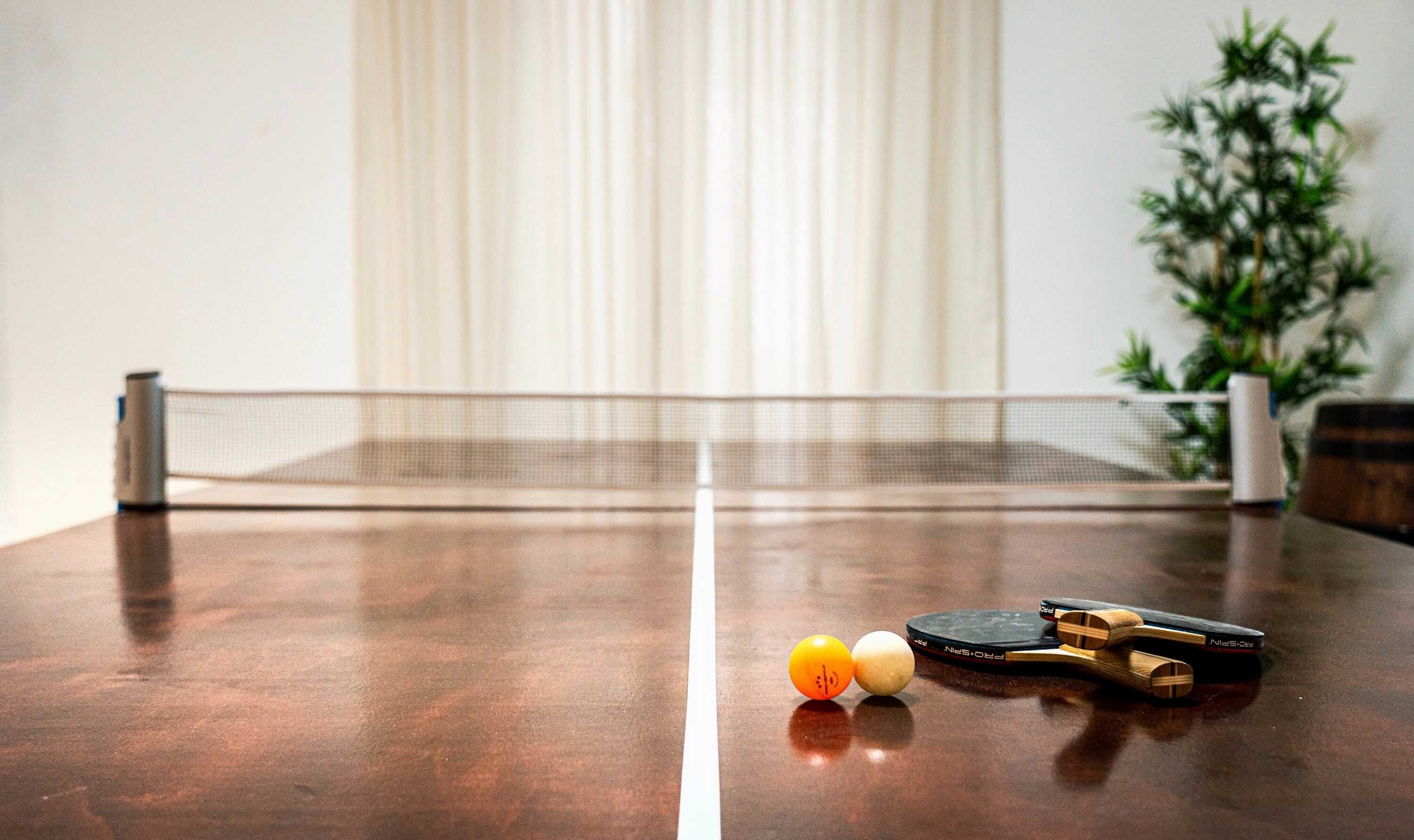 Een tafeltennistafel met een batje en twee ballen.