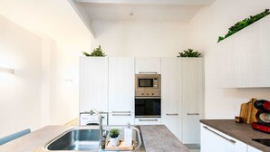 Uma cozinha moderna com armários brancos, eletrodomésticos de aço inoxidável e bancada de granito.