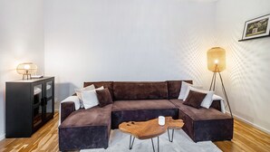 Een moderne woonkamer met een hoekbank, een houten salontafel, een kast en twee vloerlampen.