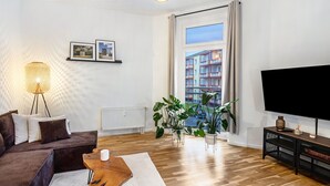 Een moderne woonkamer met een bank, een salontafel, een televisie en potplanten.