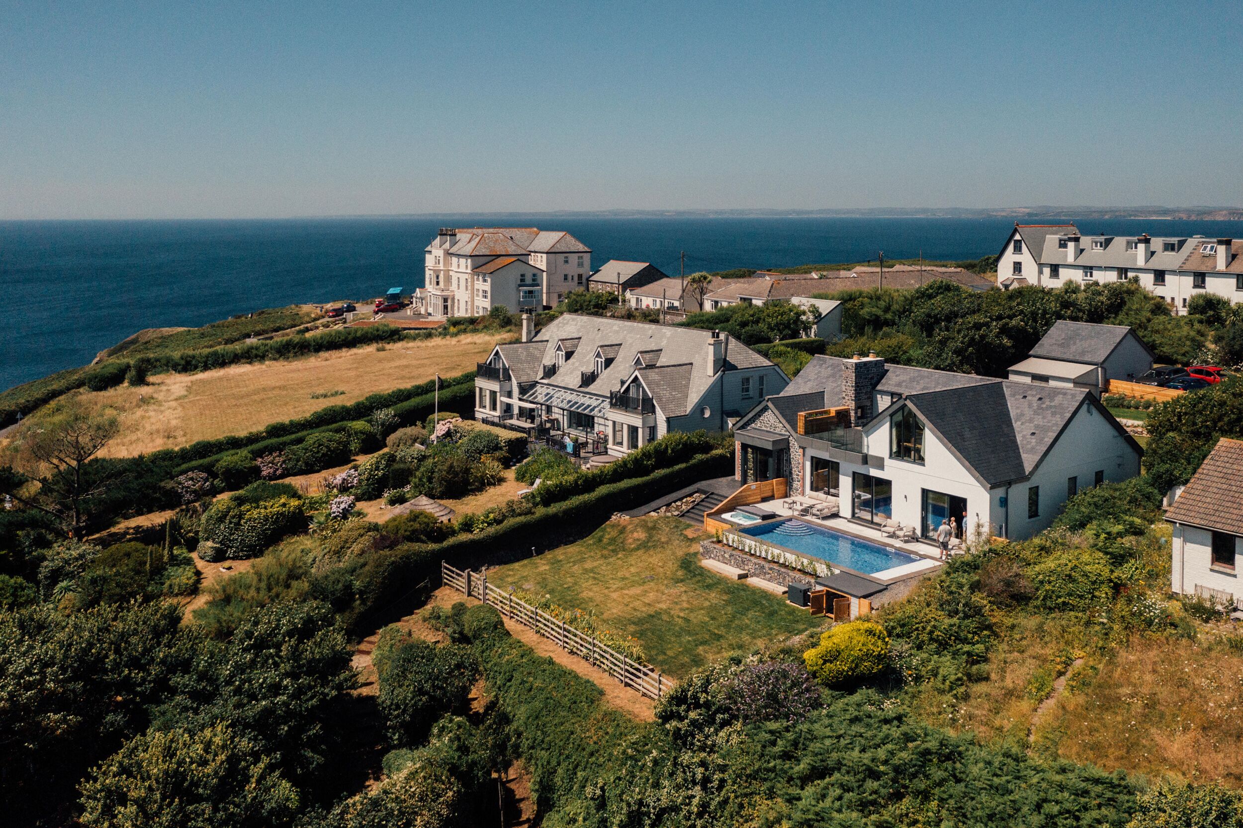 Een woongebied aan de kust met huizen, een zwembad en uitzicht op zee.