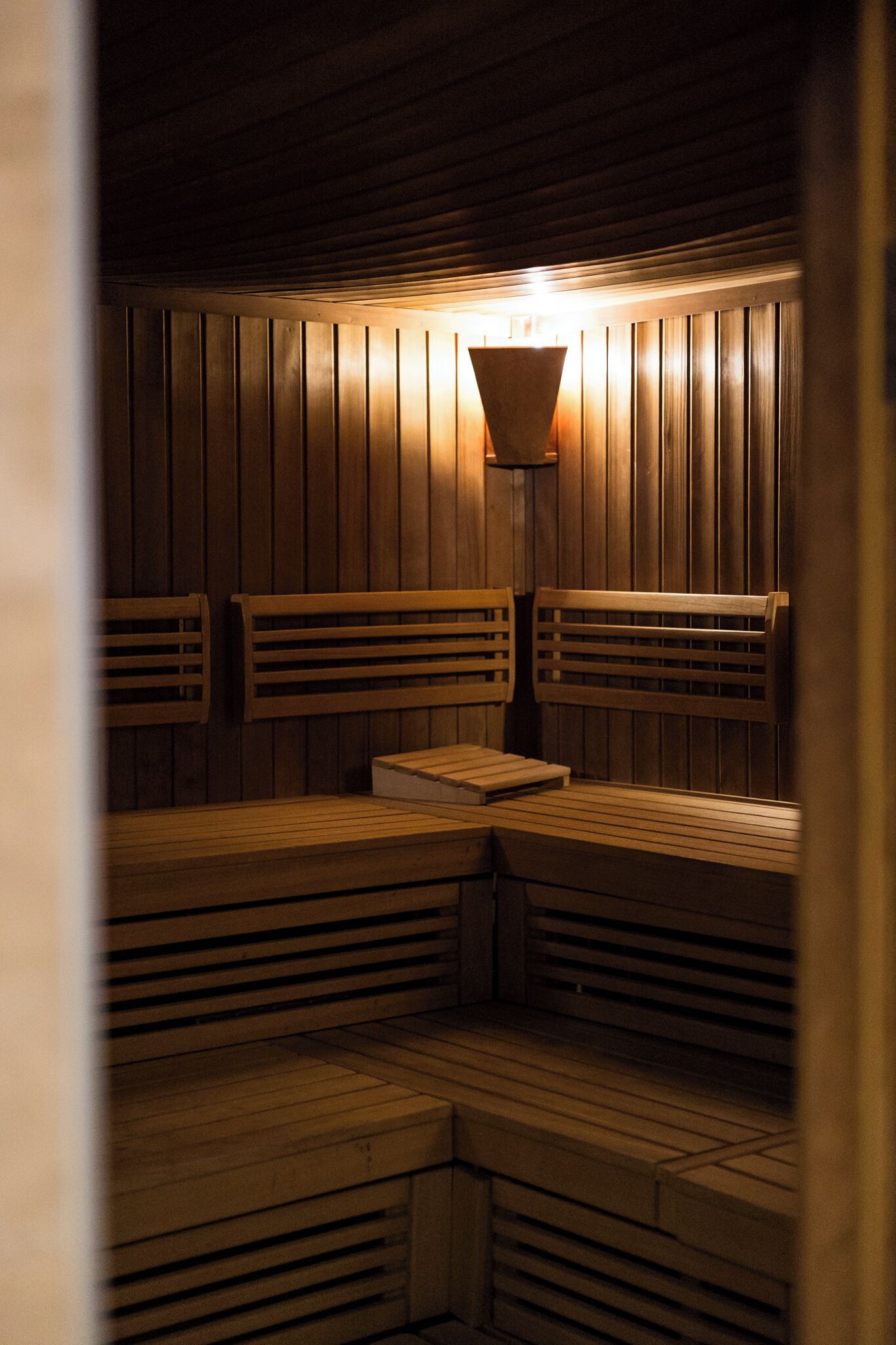 Una sauna con bancos de madera y una lámpara en el centro.