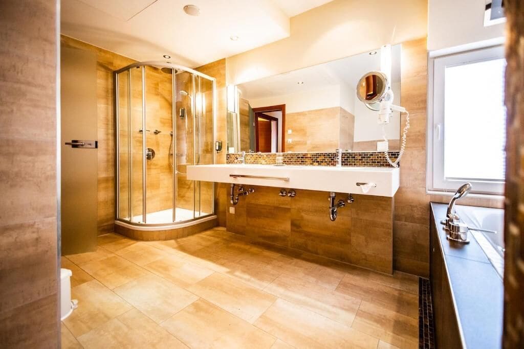 A modern bathroom with a glass-enclosed shower, a large mirror, and a vanity with a sink.