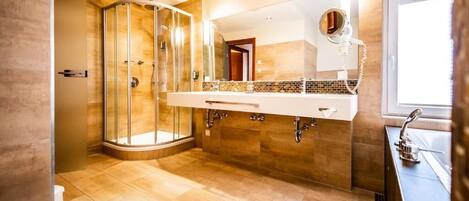 A modern bathroom with a glass-enclosed shower, a large mirror, and a vanity with a sink.