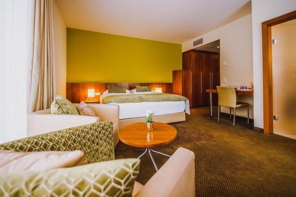 Una habitación de hotel con cama, sofá, escritorio y una mesita.