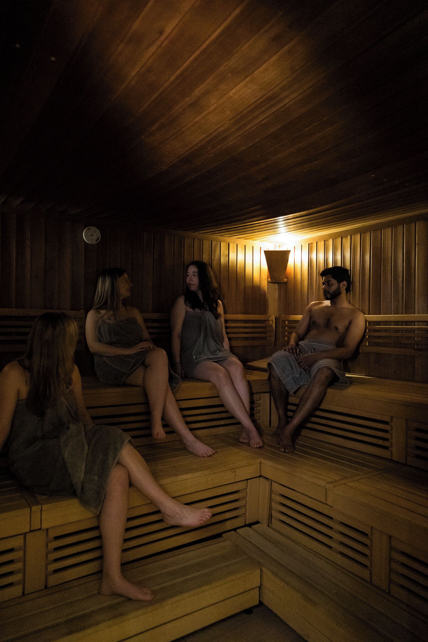 Een sauna met houten banken en een centraal lichtarmatuur.