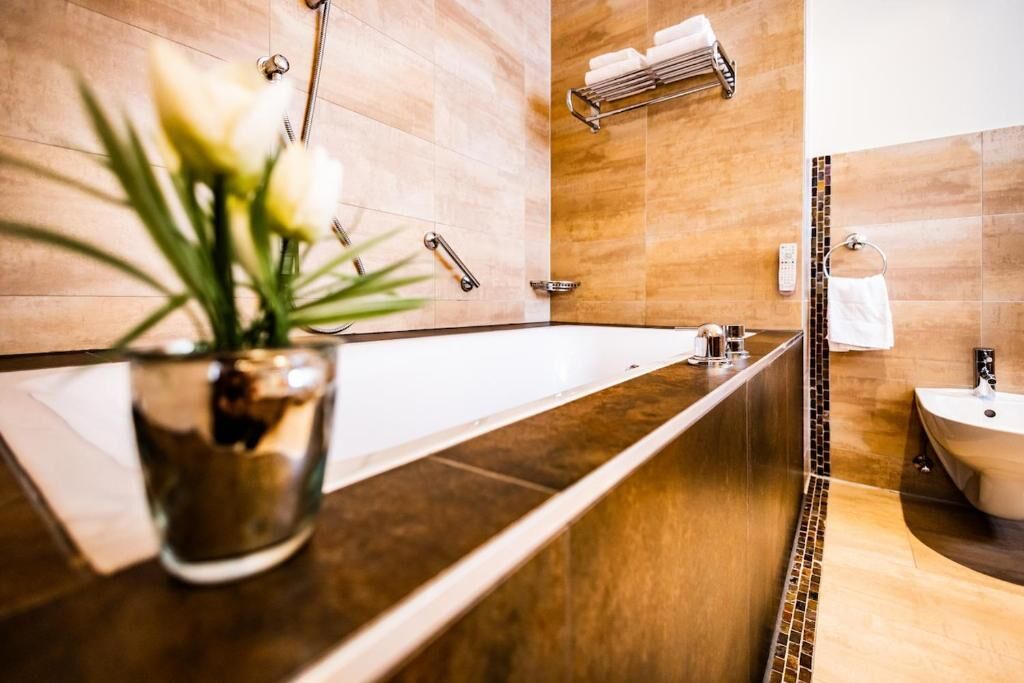 A modern bathroom with a long, narrow bathtub, a sink, and a mirror.