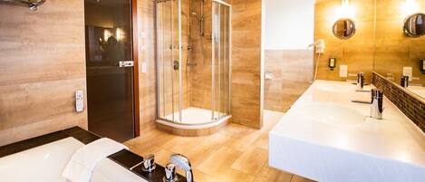 A modern bathroom with a glass-enclosed shower, a large bathtub, and two sinks.
