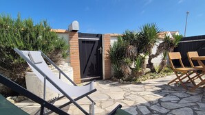 Un patio con suelo de piedra, una verja negra y sillones de descanso.