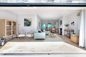 Ein geräumiges Wohnzimmer mit einer Couch, Sesseln, einem Couchtisch und einem Essbereich mit Tisch und Stühlen.