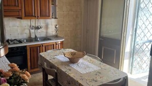 A kitchen with wooden cabinets, a sink, and a dining table with chairs. - Three-room cottage Luis (Torre Suda)