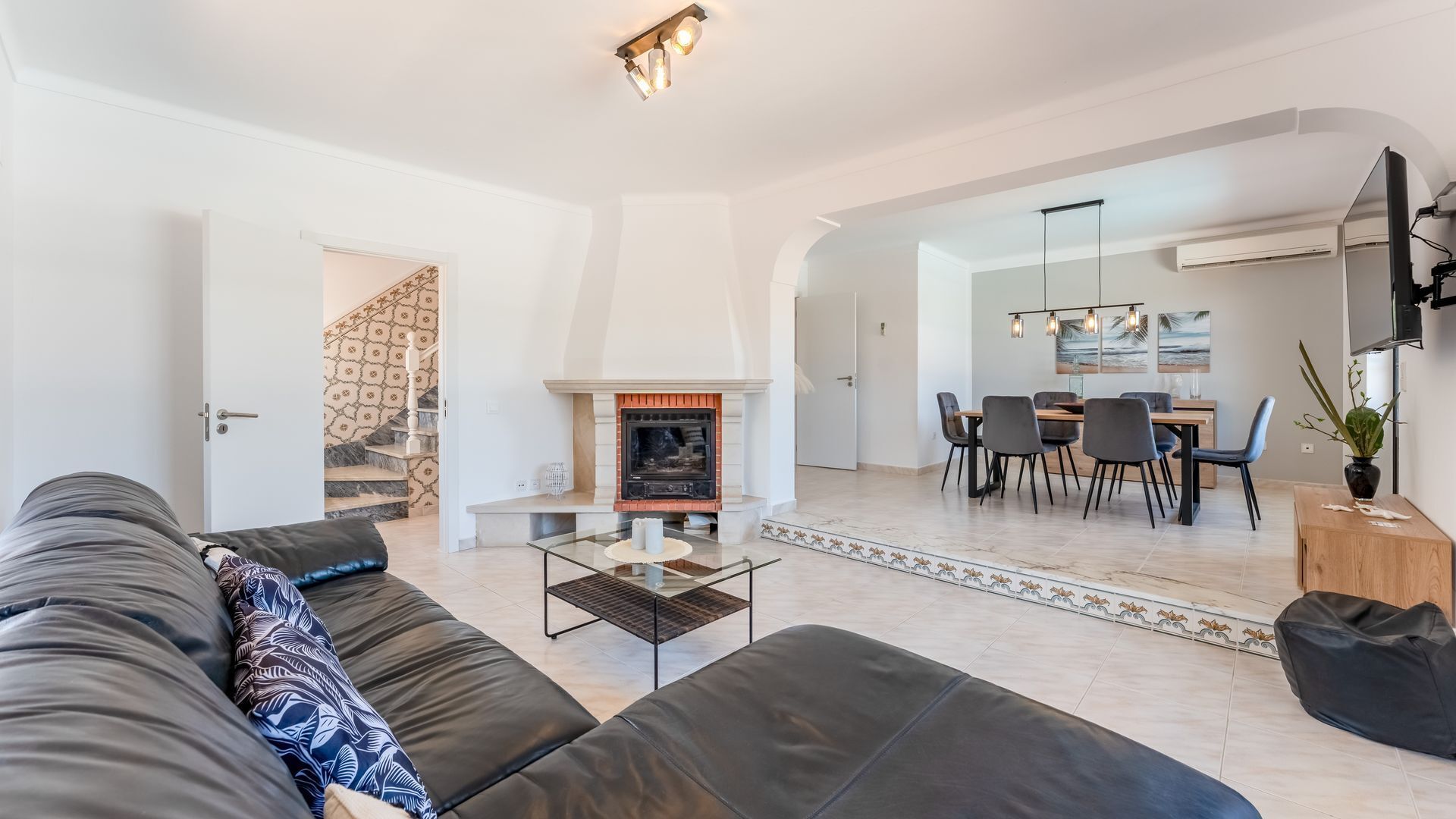 Ein modernes Wohnzimmer mit Kamin, Essbereich und Treppe.