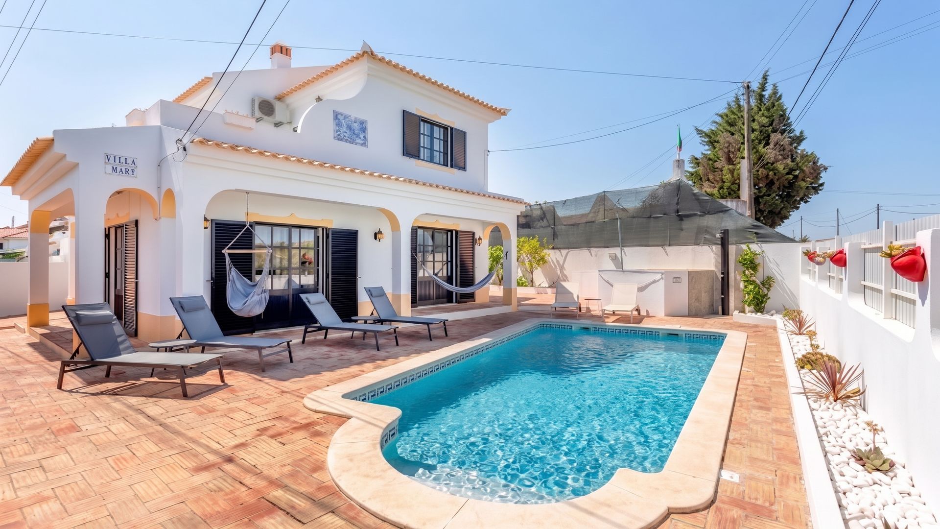 A villa with a swimming pool, outdoor seating, and a covered patio area.