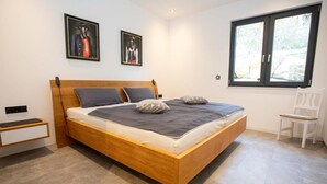 Un dormitorio moderno con una cama de madera, una mesita de noche, una silla y dos cuadros en la pared.