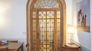 A wooden door with stained glass panels, a dining table with chairs, a lamp, and a framed picture on the wall. - Rental in Rome Frattina Atmosphere Apartment (Rome)