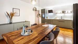 Una cocina moderna con una mesa de comedor de madera, sillas e iluminación colgante.