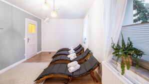 Una habitación con sillones de masaje, una planta en maceta y un ventanal con cortinas.