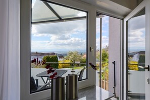 Un balcon avec une table et des chaises, une vue sur le paysage et une porte donnant sur une autre pièce.