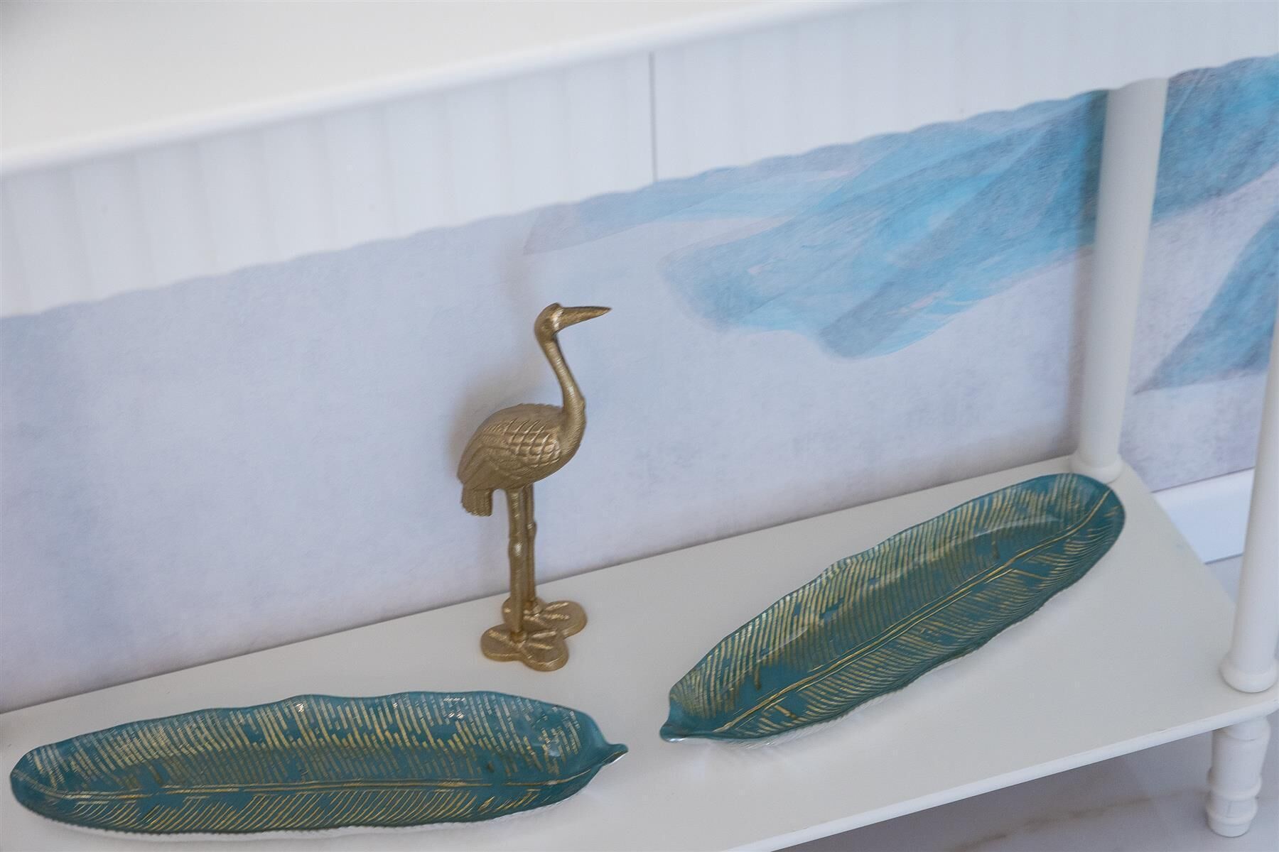 A white bench with a decorative bird and two leaves.