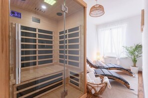 Un cuarto de sauna con paredes de vidrio, un panel de control y dos sillones reclinables.