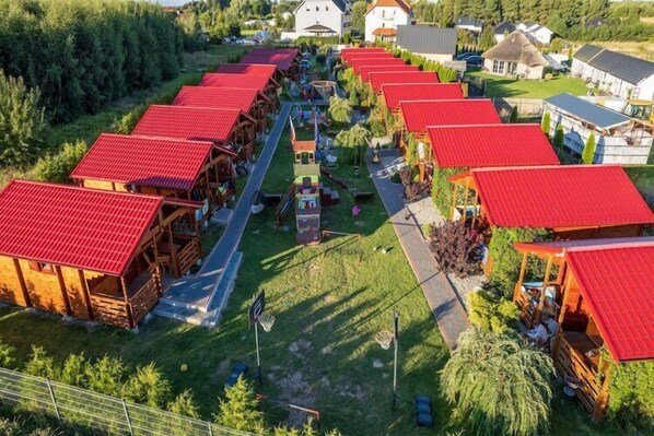 A row of cabins with red roofs, arranged in a linear fashion along a pathway.