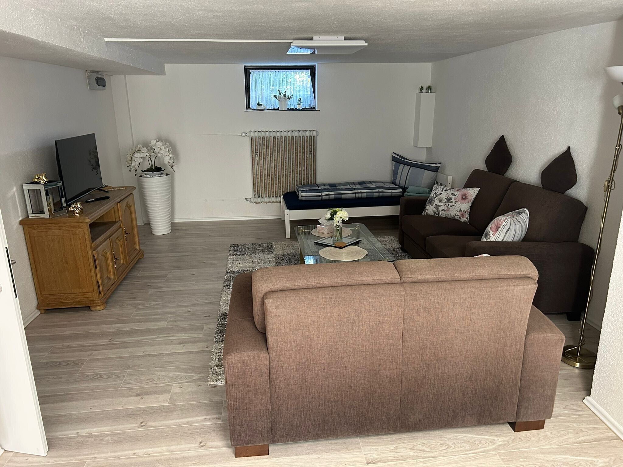 A modern living room with a sofa, a coffee table, a TV, and a radiator.