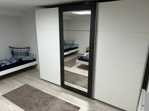 Un dormitorio con cama, armario y espejo.