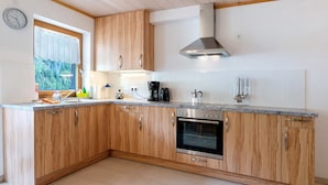 A kitchen with wooden cabinets, a built-in oven, a coffee maker, and a window with a view of greenery.