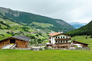 A mountain lodge with a large wooden structure, a covered patio, and a view of a valley.