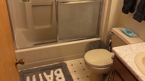 Een badkamer met een douchecabine van glas, een toilet en een wastafel.