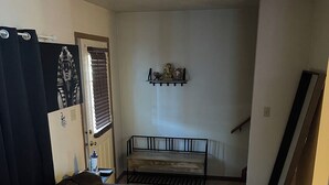 Een woonkamer met een bruine zithoek, een bijzettafeltje en een decoratieve plank met spullen.