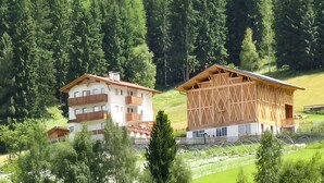 Un chalet de montagne avec une façade en bois, de nombreux balcons et une vue sur une colline boisée.