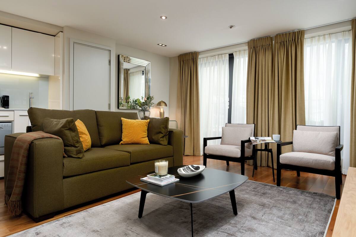 Een moderne woonkamer met een bank, fauteuils, een salontafel en een eettafel.
