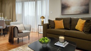 Un salon moderne avec un canapé, une table basse sur laquelle est posée une bougie, et un panier de pommes.