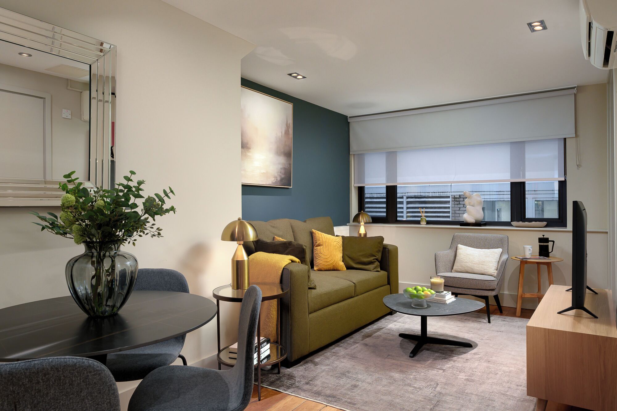 A modern living room with a sofa, coffee table, and a dining area.