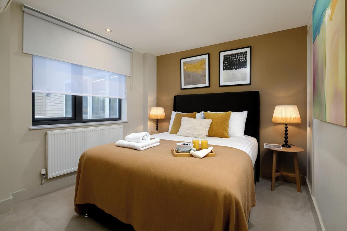 Een hotelkamer met een bed, nachtlampjes, een raam en kunst aan de muur.