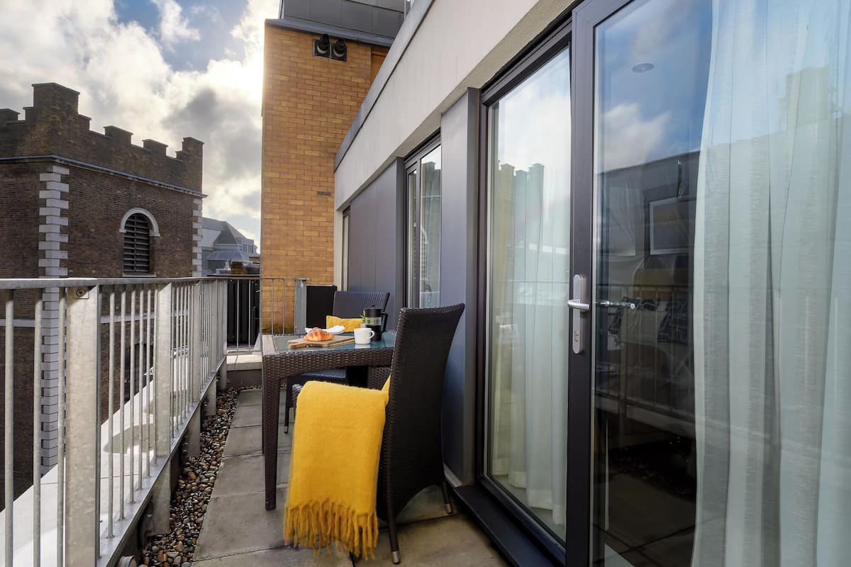 Een balkon met een tafel, stoelen en een gele dekens.